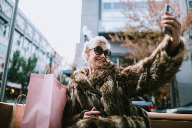 Stylish and Quirky Senior Woman Takes Selfie A fun and cheerful senior woman enjoys a day out on the town in the city of Portland, Oregon.  She wears fashionable clothing with a bit of flair and playfulness.  She takes a selfie with her smartphone to share on social networks. offbeat stock pictures, royalty-free photos & images