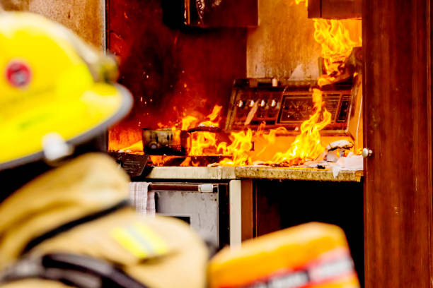 Firefighters and kitchen fire Firefighters and a stove fire. Firefighters in the foreground. kitchen on fire stock pictures, royalty-free photos & images