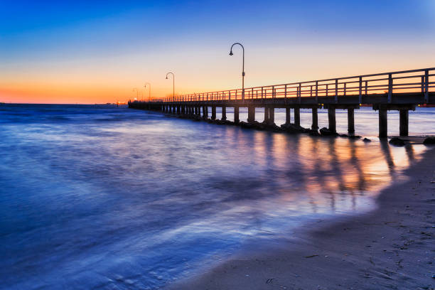 ME Port Jetty Side Set Historic timber jetty for fishing and recreation in Port Philip bay off Port Melbourne sandy beach at sunset. port melbourne melbourne stock pictures, royalty-free photos & images