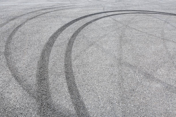 istock black tire tracks skid on asphalt road,abstract background 872673294