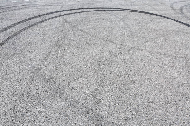 istock black tire tracks skid on asphalt road,abstract background 872673338