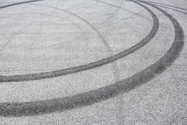 istock black tire tracks skid on asphalt road,abstract background 872673366