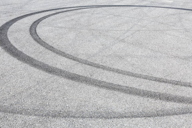 istock black tire tracks skid on asphalt road,abstract background 872673588