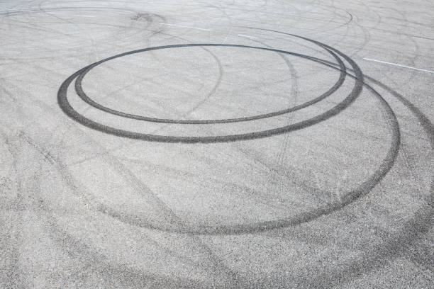 istock black tire tracks skid on asphalt road,abstract background 872673592