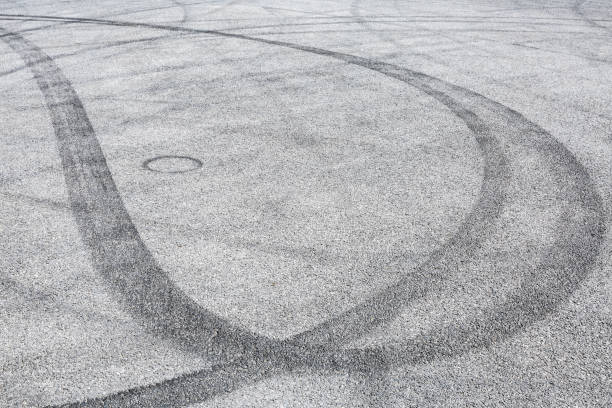 istock black tire tracks skid on asphalt road,abstract background 872673916