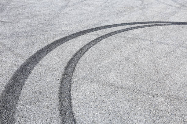 istock black tire tracks skid on asphalt road,abstract background 872674284