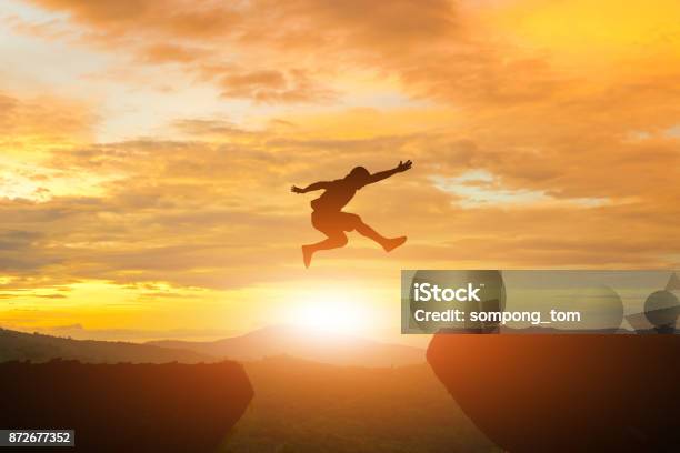 Men Jump Cliff Sun Light Over Silhouette Stock Photo - Download Image Now - Jumping, Challenge, Conquering Adversity