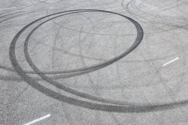istock black tire tracks skid on asphalt road,abstract background 872680188