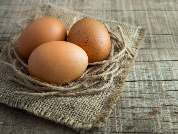 istock 3 eggs on a old sack with rope on wooden background, eggs with vintage tone 872680292