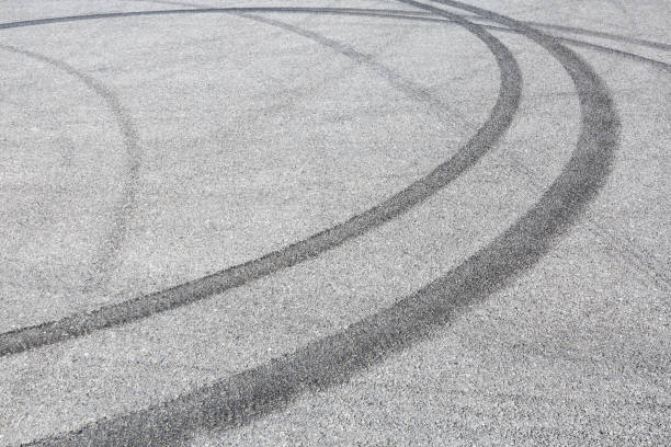 istock black tire tracks skid on asphalt road,abstract background 872680820