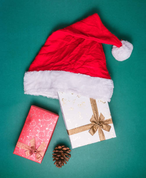 istock Top view of gift boxes with santa hat on green background. 872680956
