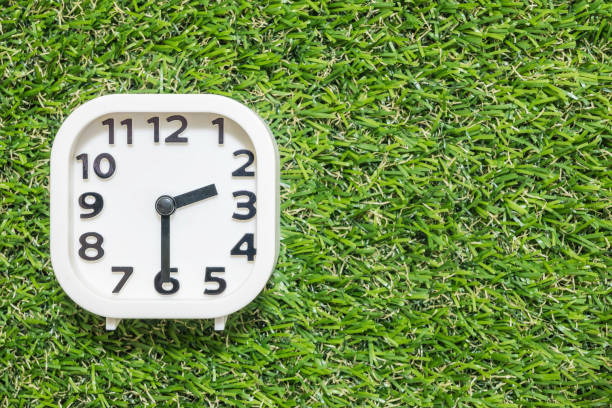 istock Closeup white clock for decorate show a half past two o'clock or 2:30 p.m. on green artificial grass floor textured background with copy space 872684812