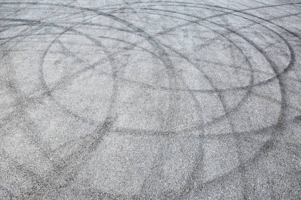 istock black tire tracks skid on asphalt road,abstract background 872687144
