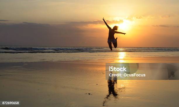 Silhouette Of Young Happy Asian Woman In Bikini Jumping Excited On Sunset Beach Having Fun In Healthy Lifestyle Stock Photo - Download Image Now