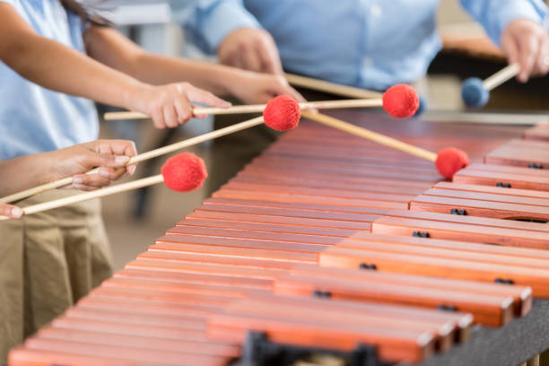 Unrecognizable children play xylophone in music class In this closeup, all are unrecognizable as two elementary band students stand next to their teacher and play the xylophone with him. teacher classroom child education stock pictures, royalty-free photos & images