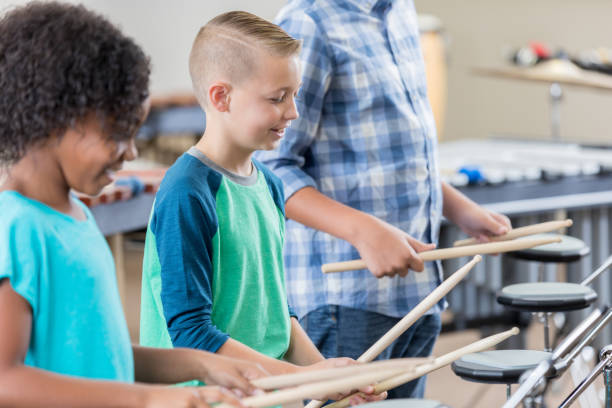 istock Young boy practices drums with teacher and schoolmate 872698040