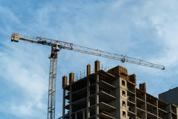 istock Crane lifting concrete mixer container against blue sky 872727926