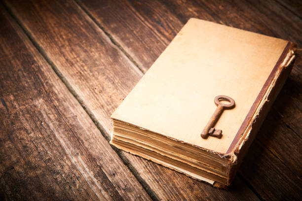 Antique book and old key over rustic wooden background.