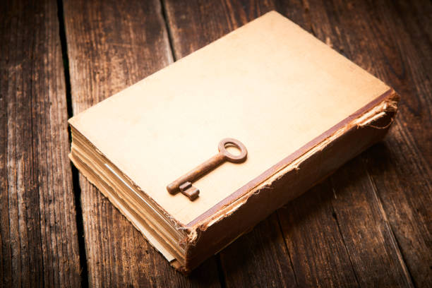 istock Antique book and old key over rustic wooden background. 872739524