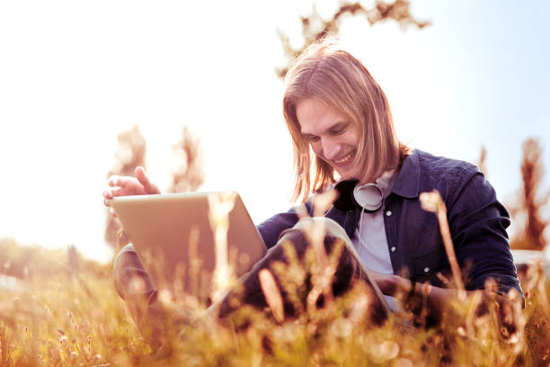 istock Young man in a park enjoying with laptop. 872762280