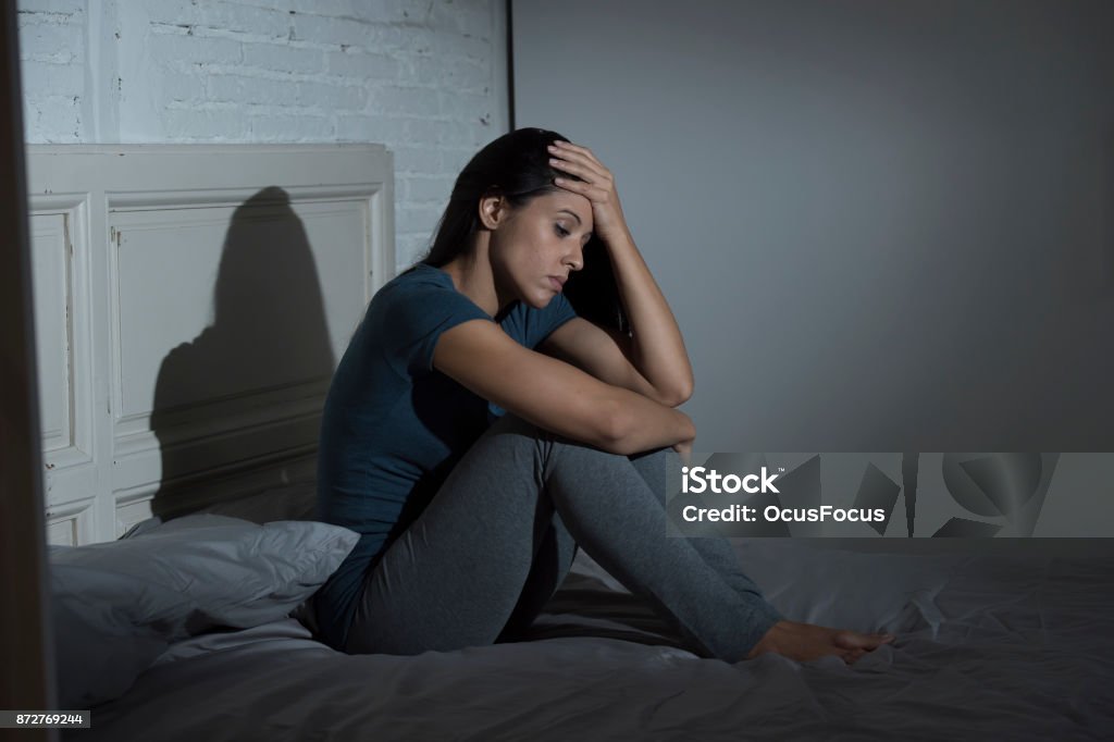 young beautiful sad and depressed Latin woman sitting on bed at home bedroom looking frustrated and worried suffering depression and headache young beautiful sad and depressed Latin woman sitting on bed at home bedroom looking frustrated and worried suffering depression and headache in relationship and life problems concept Bed - Furniture Stock Photo