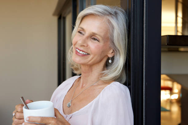 istock smiling older woman standing with cup of coffee 872772700