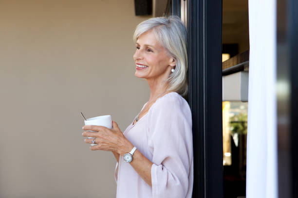istock attractive older woman standing with cup of coffee 872772704