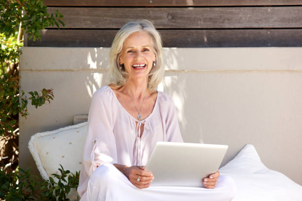 istock older woman sitting and using laptop outside 872772726