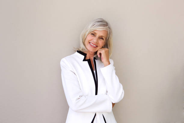 istock Smiling older business woman standing against wall 872772892