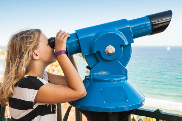 istock Girl looking through a stationary paid telescope 872776484