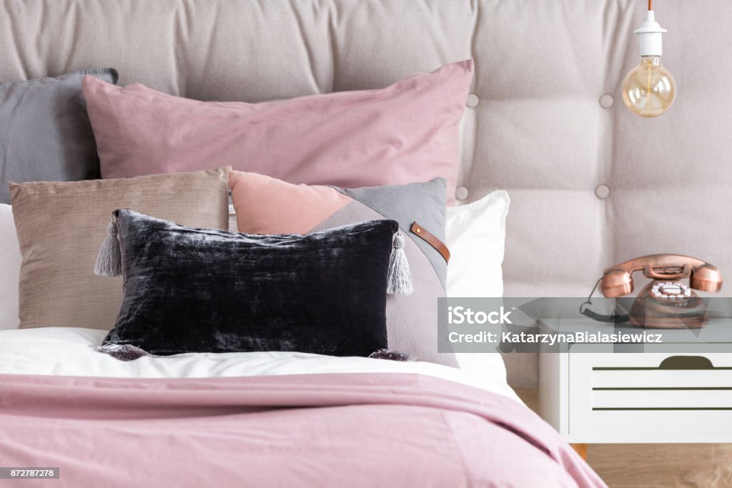 Copper phone on white nightstand Metallic copper phone on white nightstand and bulb light in retro interior of stylish bedroom with pink linen and velour pillow Bed - Furniture Stock Photo