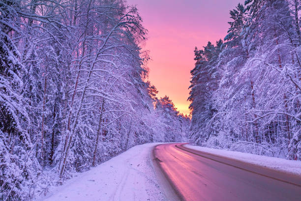 winterlandschaft mit sonnenuntergang, straße und wald - lane stock-fotos und bilder