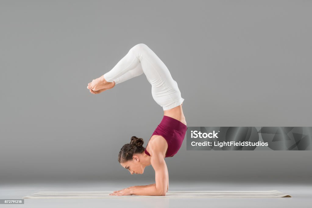 woman doing yoga exercise young woman performing yoga headstand with bent legs pose Headstand Stock Photo