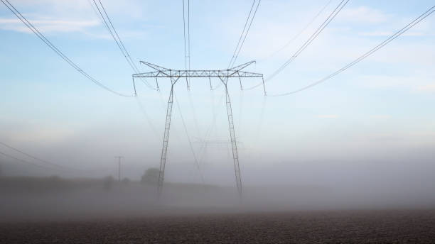 Power lines in a foggy landscape stock photo