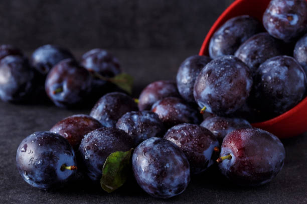 istock ripe plums over dark table background close up 872803568
