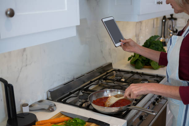 Woman using digital tablet while cooking food