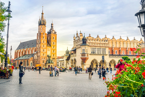 main market square with Adam Mickiewicz staue and saint mary´s church in the background in Krakow under blue sky