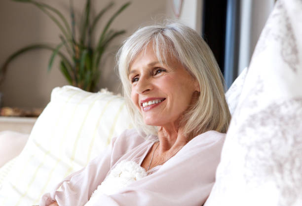 istock happy older woman sitting on couch relaxed and smiling 872814292