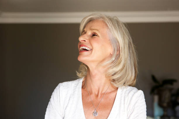 istock laughing older woman standing inside home 872814460