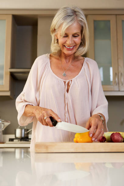 istock happy older woman in kitchen cutting fresh vegetables 872814560