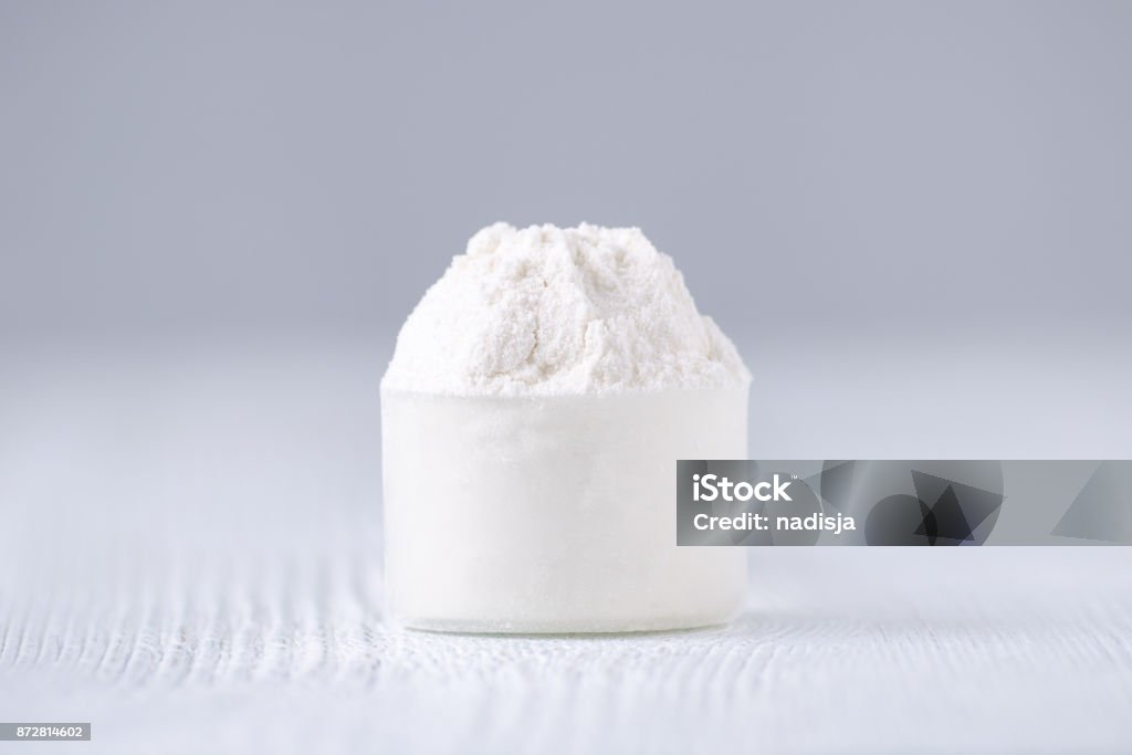 a scoop with white powder, selective focus a scoop with white powder on gray background, selective focus Ground - Culinary Stock Photo