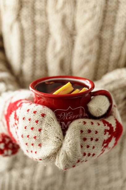 closeup foto de las manos en guantes tejidos con rojo taza con ponche delicioso caliente. - mulled wine punch cocktail christmas fotografías e imágenes de stock