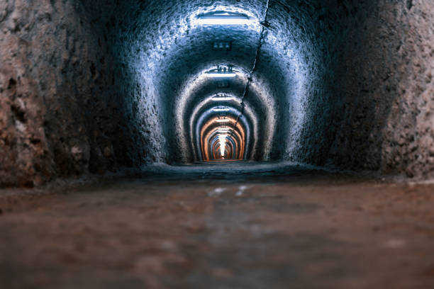 istock Illumitated underground arched tunnel with rough walls 872832664