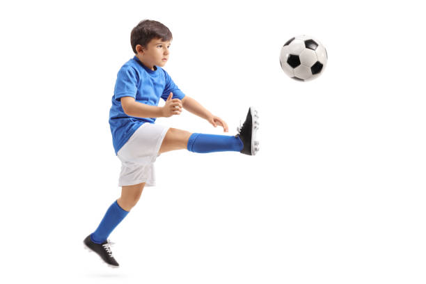 pequeño jugador de fútbol pateando una pelota de fútbol en el aire - volley kick fotografías e imágenes de stock