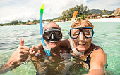 istock Senior happy couple taking selfie in tropical sea excursion with water camera - Boat trip snorkeling in exotic scenarios - Active retired elderly and fun concept around the world - Warm bright filter 872833094