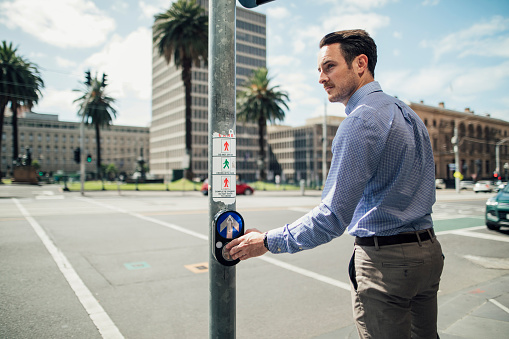 Millennial businessman is using a public crossing while commuting in Melbourne, Victoria.