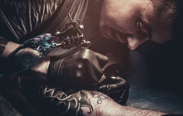 Tattoo master making tattoo on customer's leg