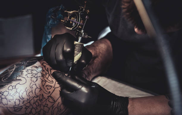 istock Tattoo master making tattoo on customer's leg 872843730