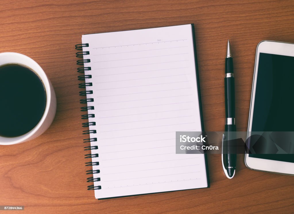 Diretamente acima do local de trabalho com bloco de notas aberto, café, Smartphone e caneta - Foto de stock de Caderno de Anotação royalty-free