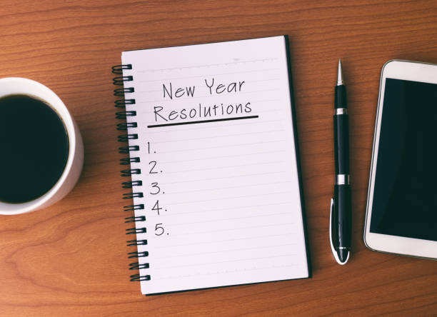 neujahr resolutionen liste auf notepad auf holz schreibtisch - determination new years eve list aspirations stock-fotos und bilder